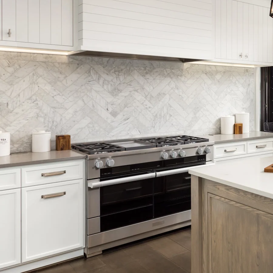 Marble herringbone backsplash behind a professional range, Carnegie Hill kitchen remodel