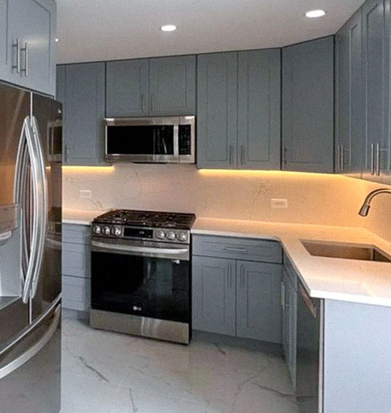 Gas range and quartz counter run with under-cabinet lighting in a Park Avenue co-op kitchen