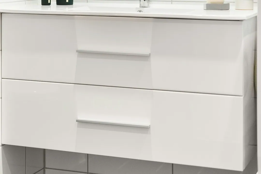 Floating white vanity with a chrome faucet and dark floor tile in a renovated Manhattan bathroom