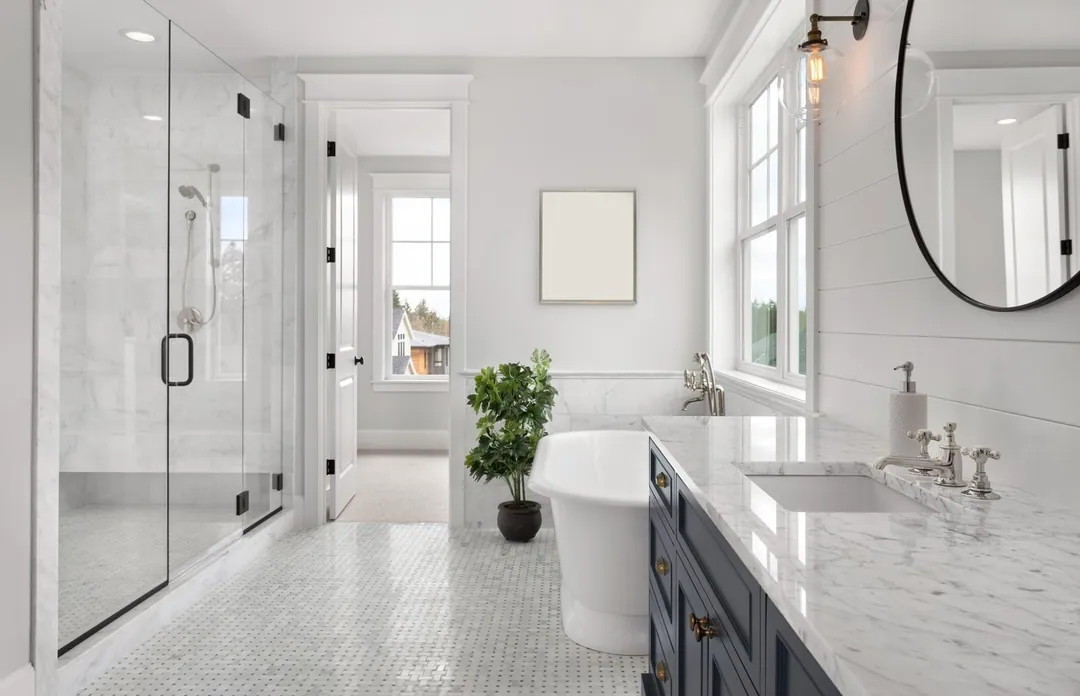Classic white marble bathroom renovation with a glass shower, freestanding tub and a navy vanity