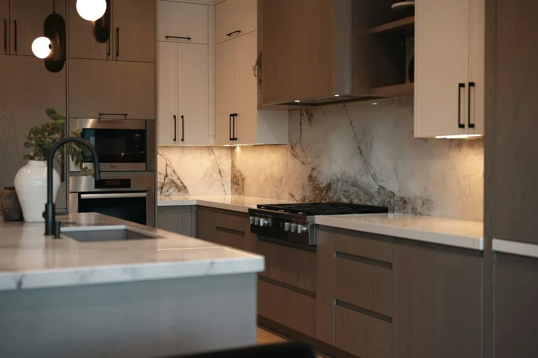 Walnut and marble kitchen renovation in Manhattan with a slab backsplash, gas range and under-cabinet lighting