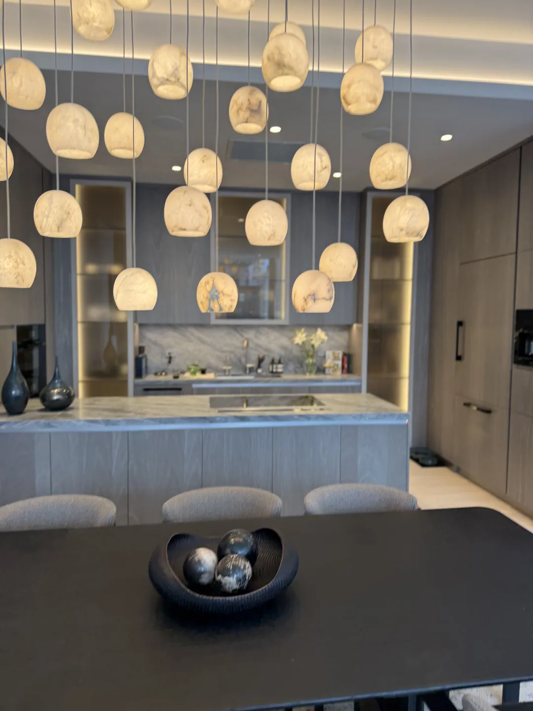 Kitchen island with alabaster pendant lights and grey cabinetry in a Manhattan apartment renovated by Home Design & Co