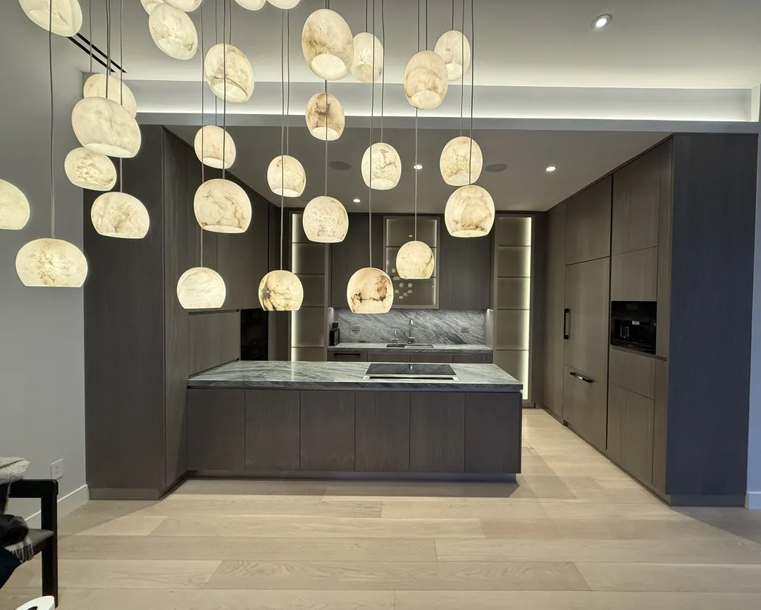 Open Manhattan kitchen renovation with a cluster of alabaster pendant lights above a stone-topped island