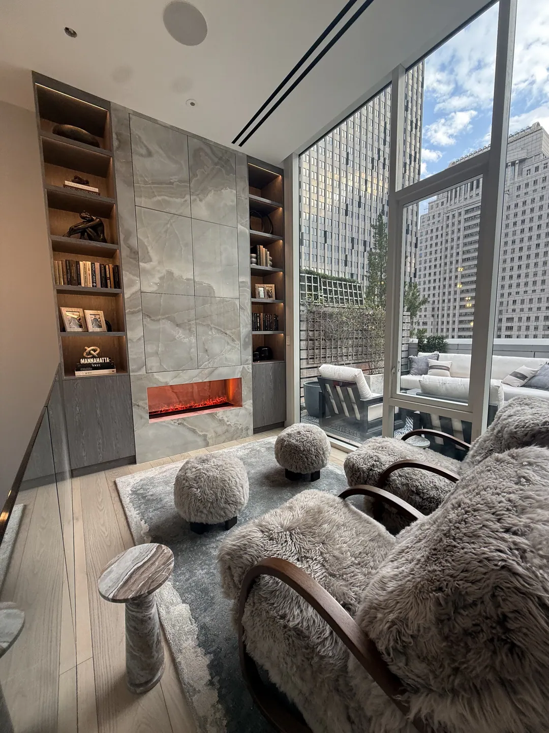 Full apartment renovation in Manhattan: living room with a stone fireplace wall and built-in shelving